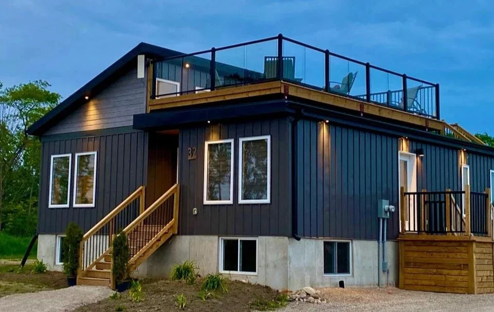A modern lakeside home with a rooftop glass deck at dusk, managed by Ben Brewer Homes on the Lake Huron shore.